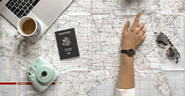 Person planning a trip with its camera, map, laptop and passport.
